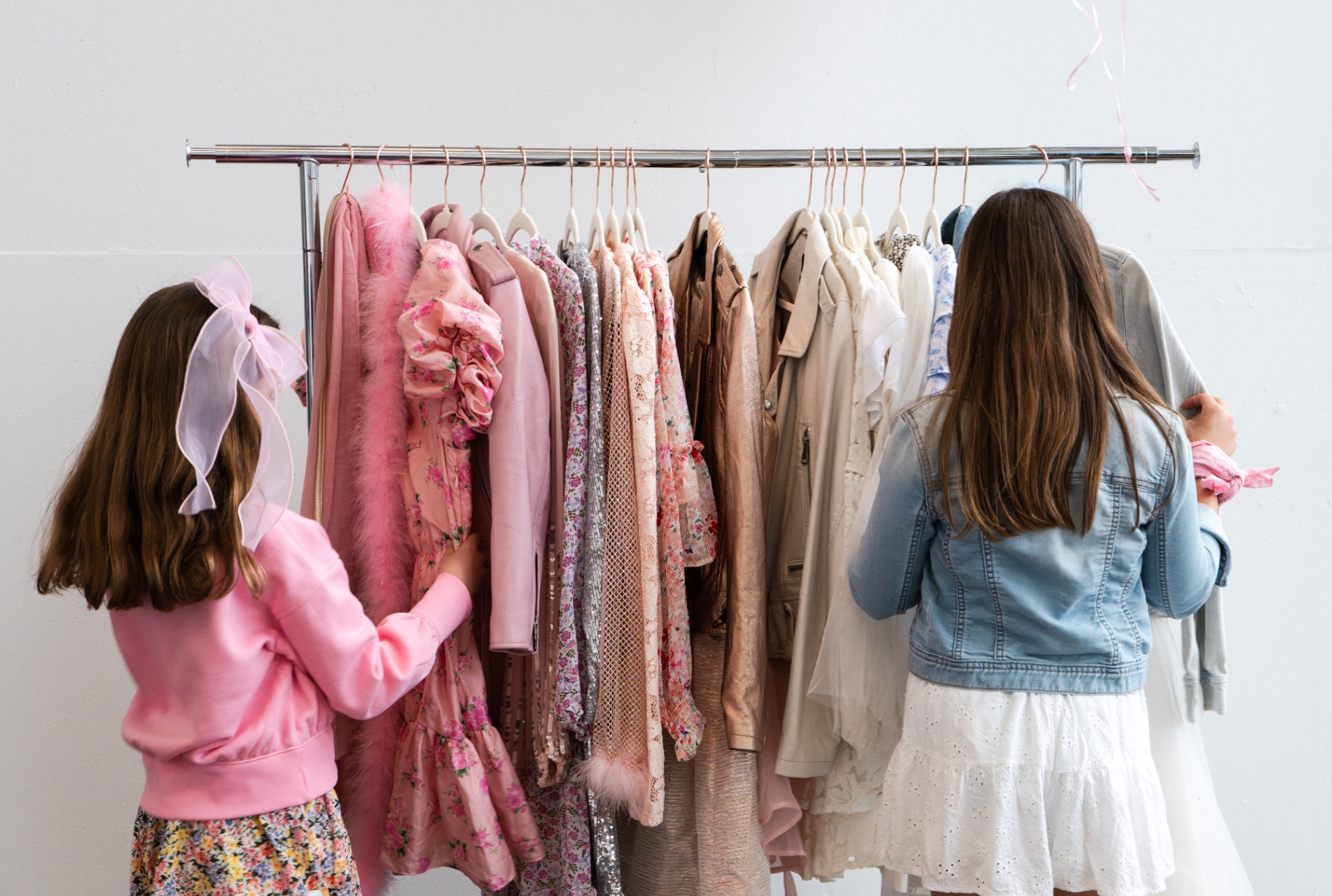 Students browsing a rack of pink editorial wardrobe pieces