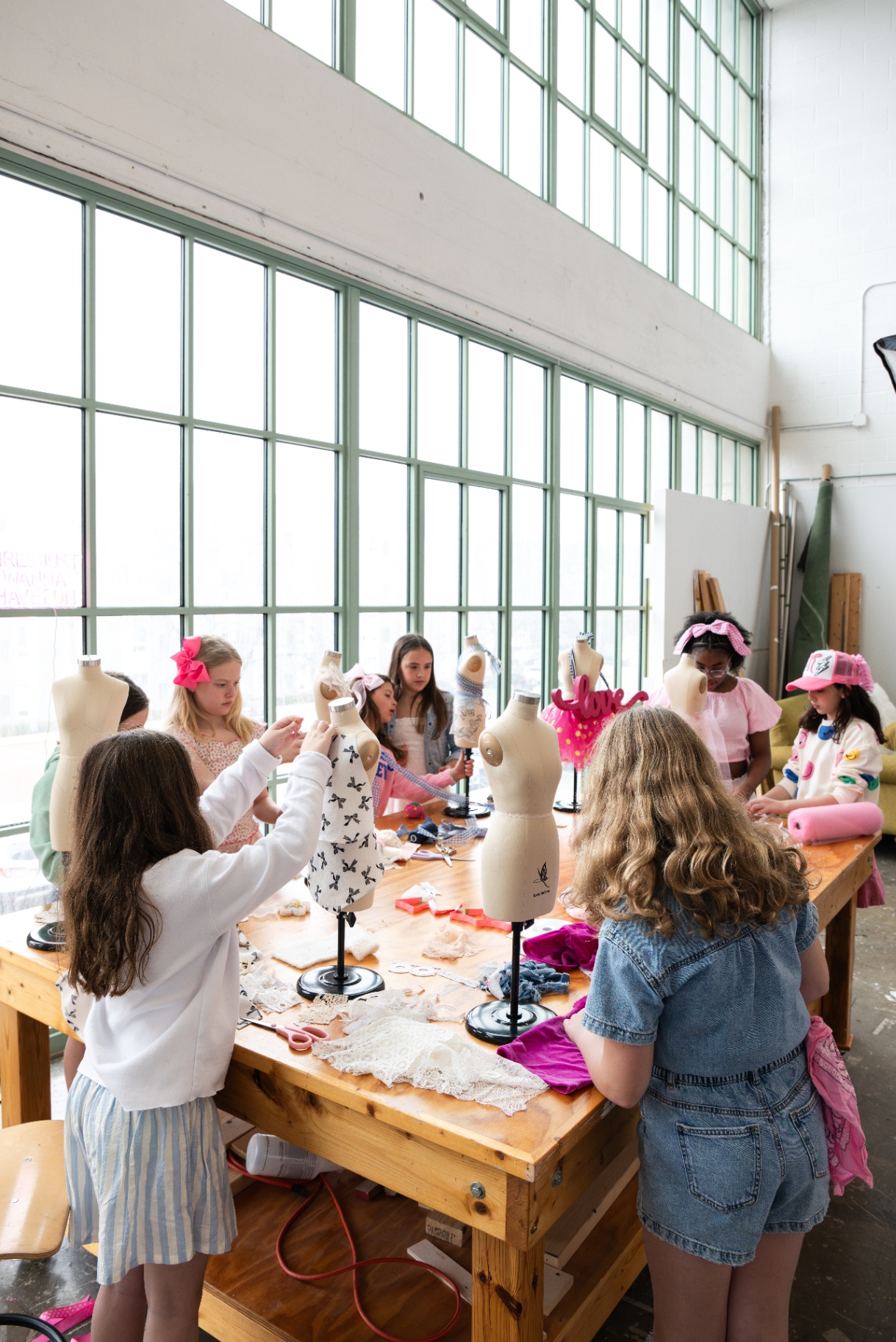 Students collaborating around dress forms at a large classroom table